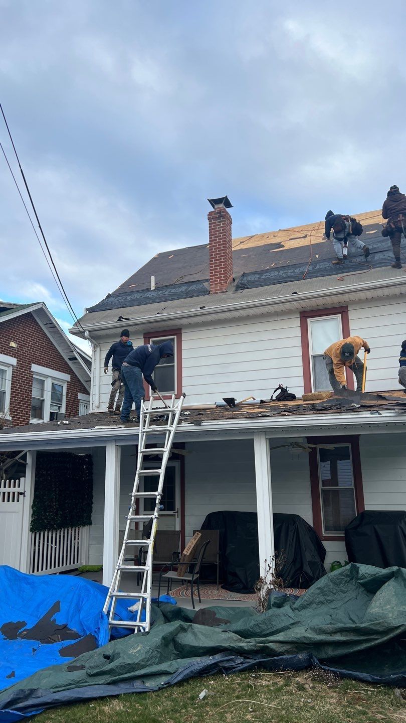 Joyland Roofing crew removing old shingles during a roof replacement project on East Simpson Street in Shepherdstown, PA.
