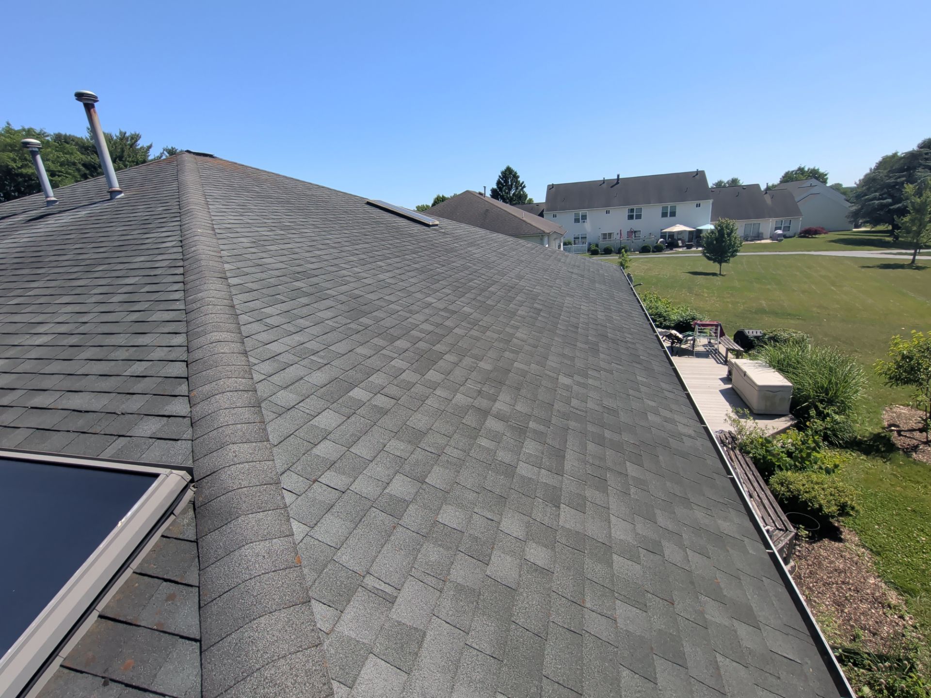 Gray shingle roof overlooking a grassy suburban yard with houses in the distance