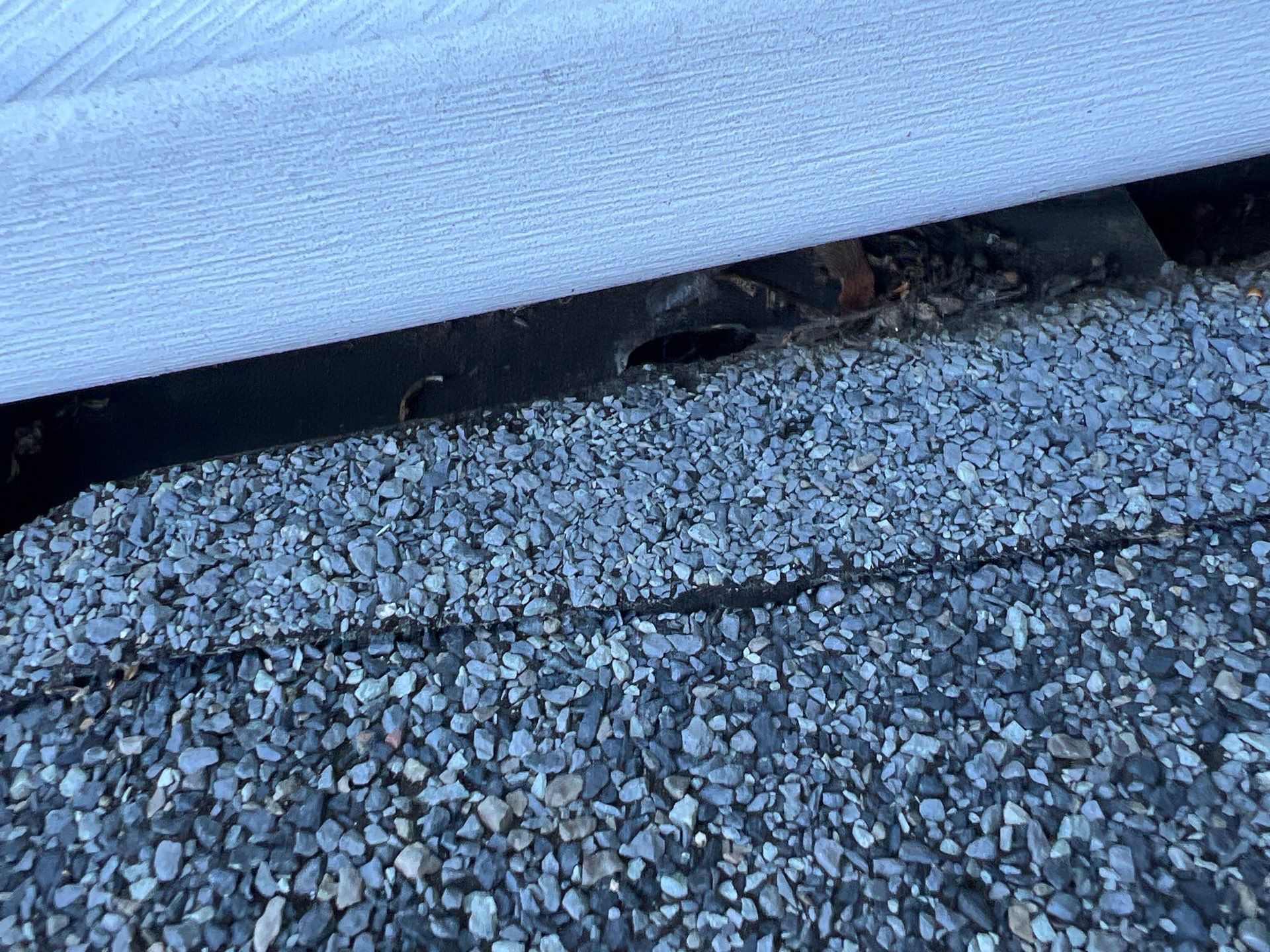 Close-up of a flat roof edge inspection showing the roof membrane, gravel surface, and drainage area on Seville Drive in Red Lion, PA.