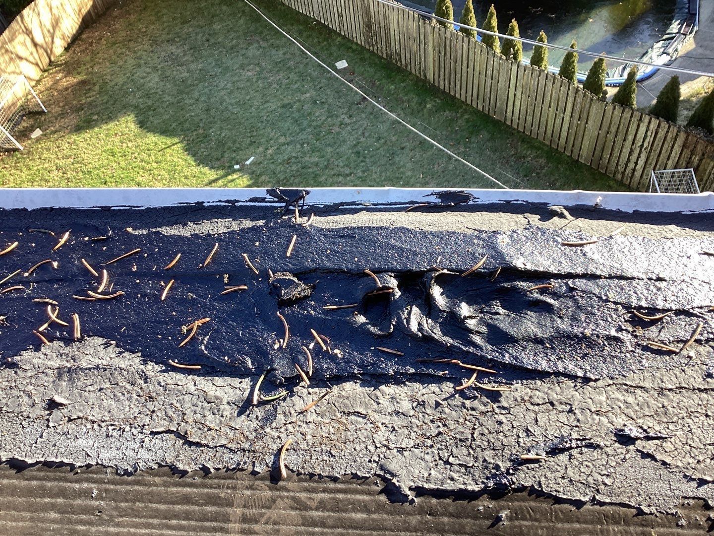 Close-up of an aging flat roof with cracked coating, weathered membrane, and deteriorated roof surface on Levering Circle in Bala Cynwyd, PA