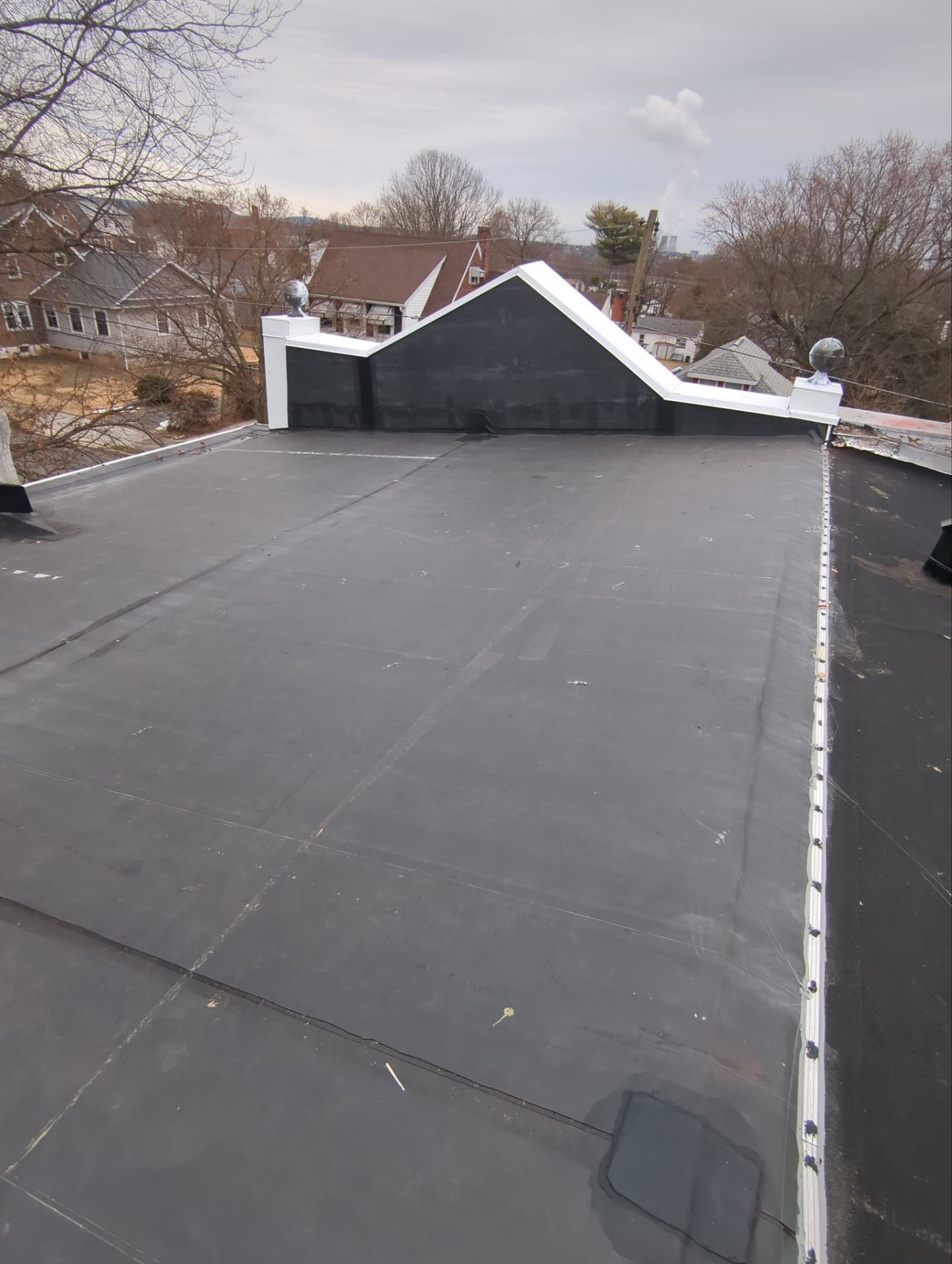 Completed flat roof replacement with white coping and black membrane roofing on East Vine Street in Pottstown, PA