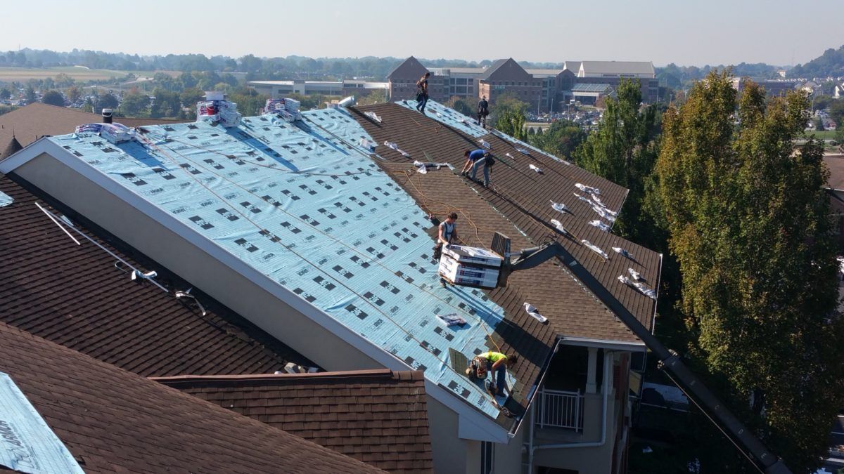Roofing crew working on a house roof on a sunny day.
