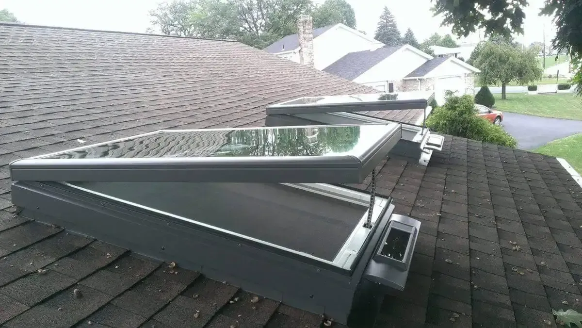 Three open skylights on a dark shingle roof, grey frames, partially open.