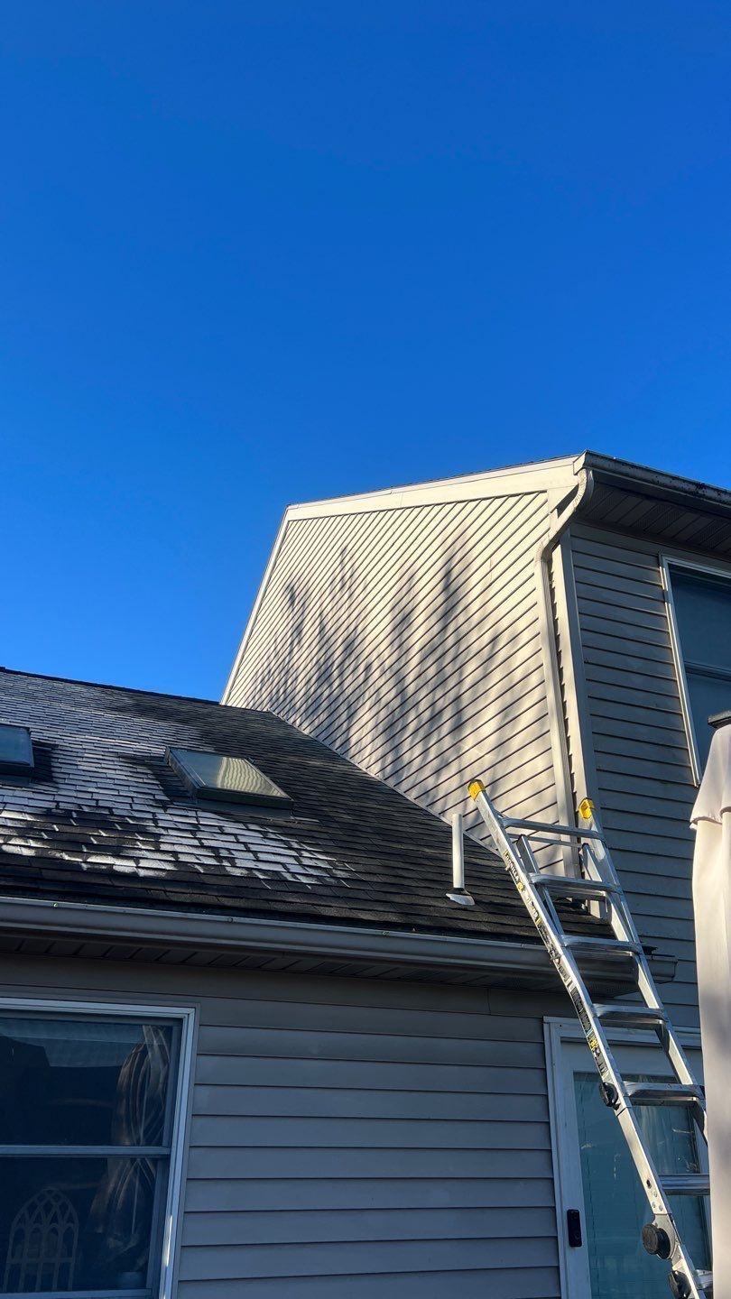 Ladder leaning against a house roof under a clear blue sky