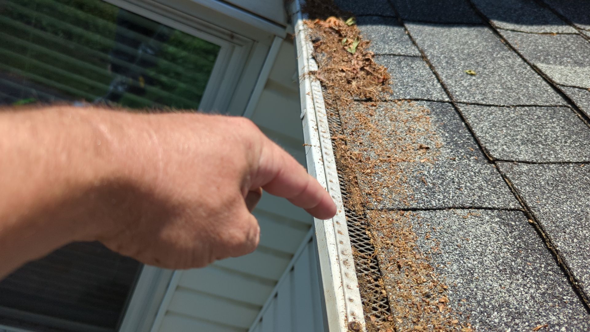 Close-up of gutter protection system and roof edge inspection on East Bainbridge Street in Elizabethtown, PA showing debris accumulation affecting roof drainage performance.