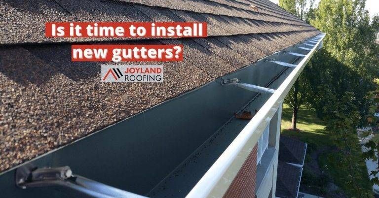 A close-up view of a shingled roof and installed gutters, with text overlay asking,