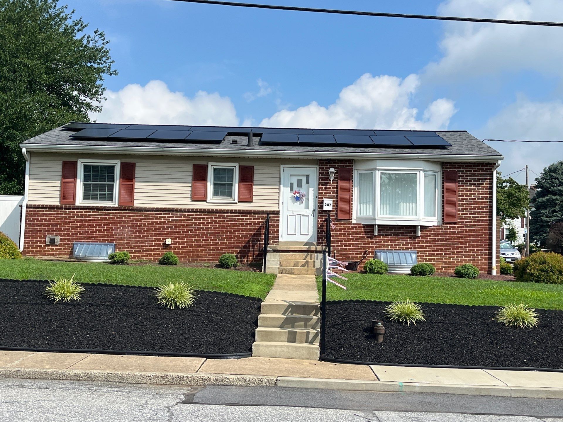 Single-story brick home on Hillcrest Road with a newly installed asphalt shingle roof and rooftop solar panels.