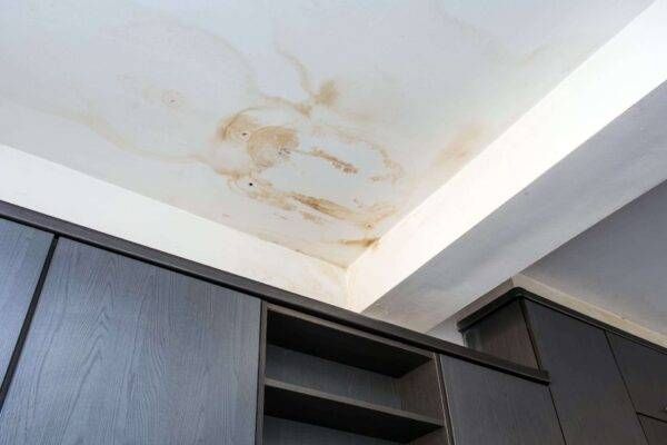 Water damage stain on a white ceiling above dark cabinets.