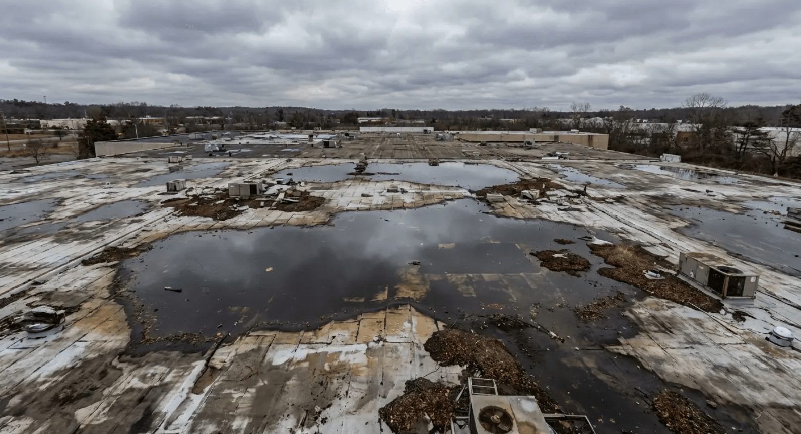 Ponding water on commercial flat roof accelerating membrane breakdown and reducing lifespan