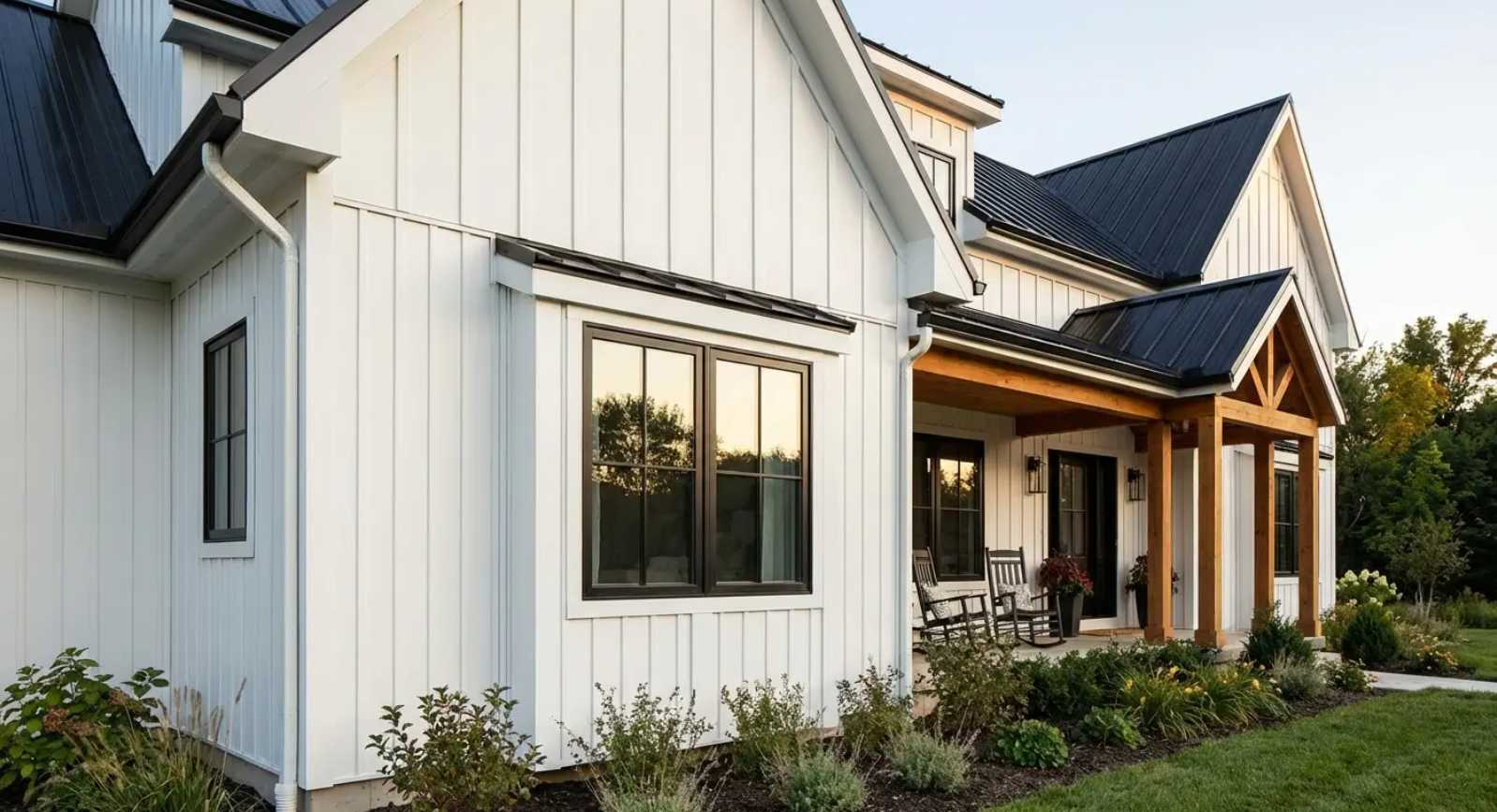 White farmhouse with black roof and trim, wooden porch, and landscaping.