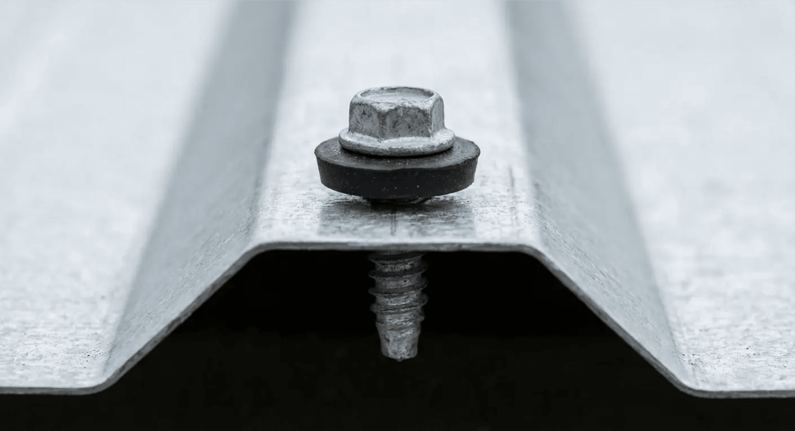 Close-up of a metal roofing seam with a bolt and washer fastening the panels together