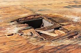 Damaged wooden floor with a large hole.