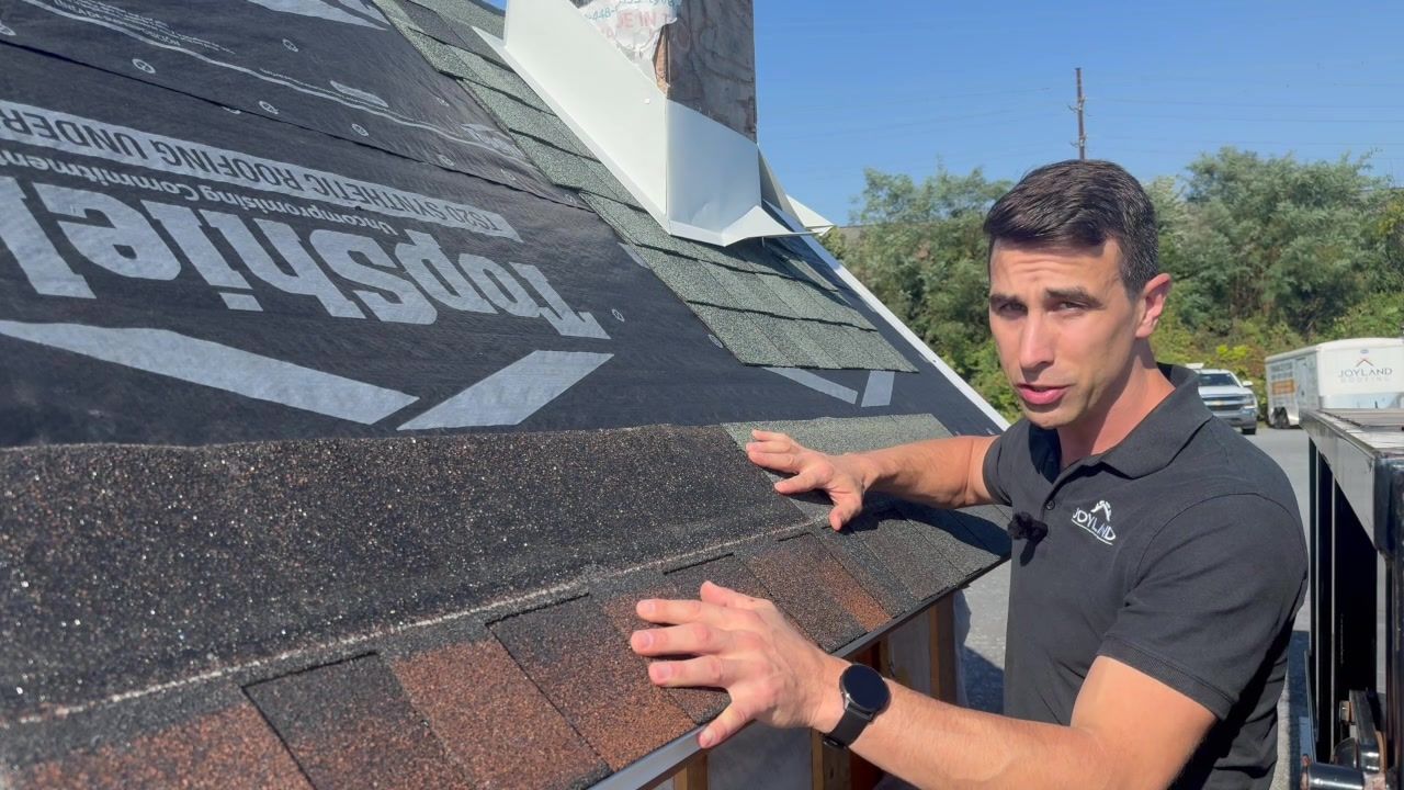 John Esh demonstrates how overlapping asphalt shingles protect the joints in the row below.