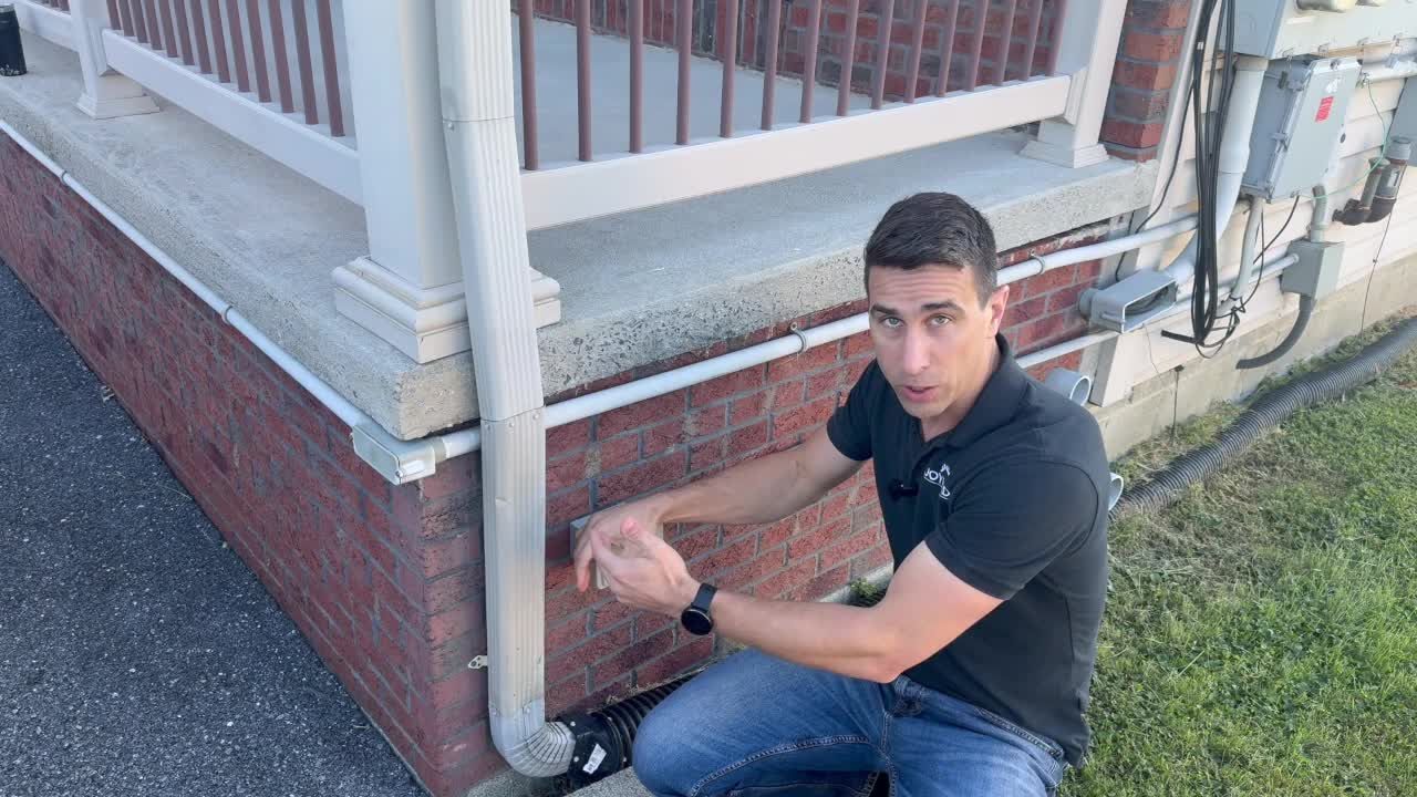 Joyland Roofing demonstration of a downspout and its connection to underground drainage