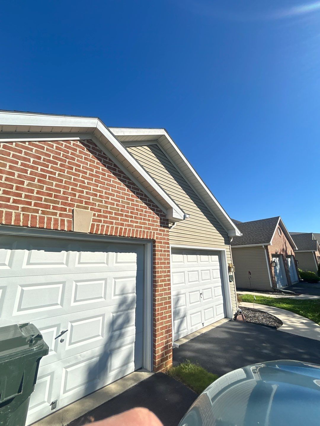 Row of brick townhouses with white garage doors under a bright blue sky