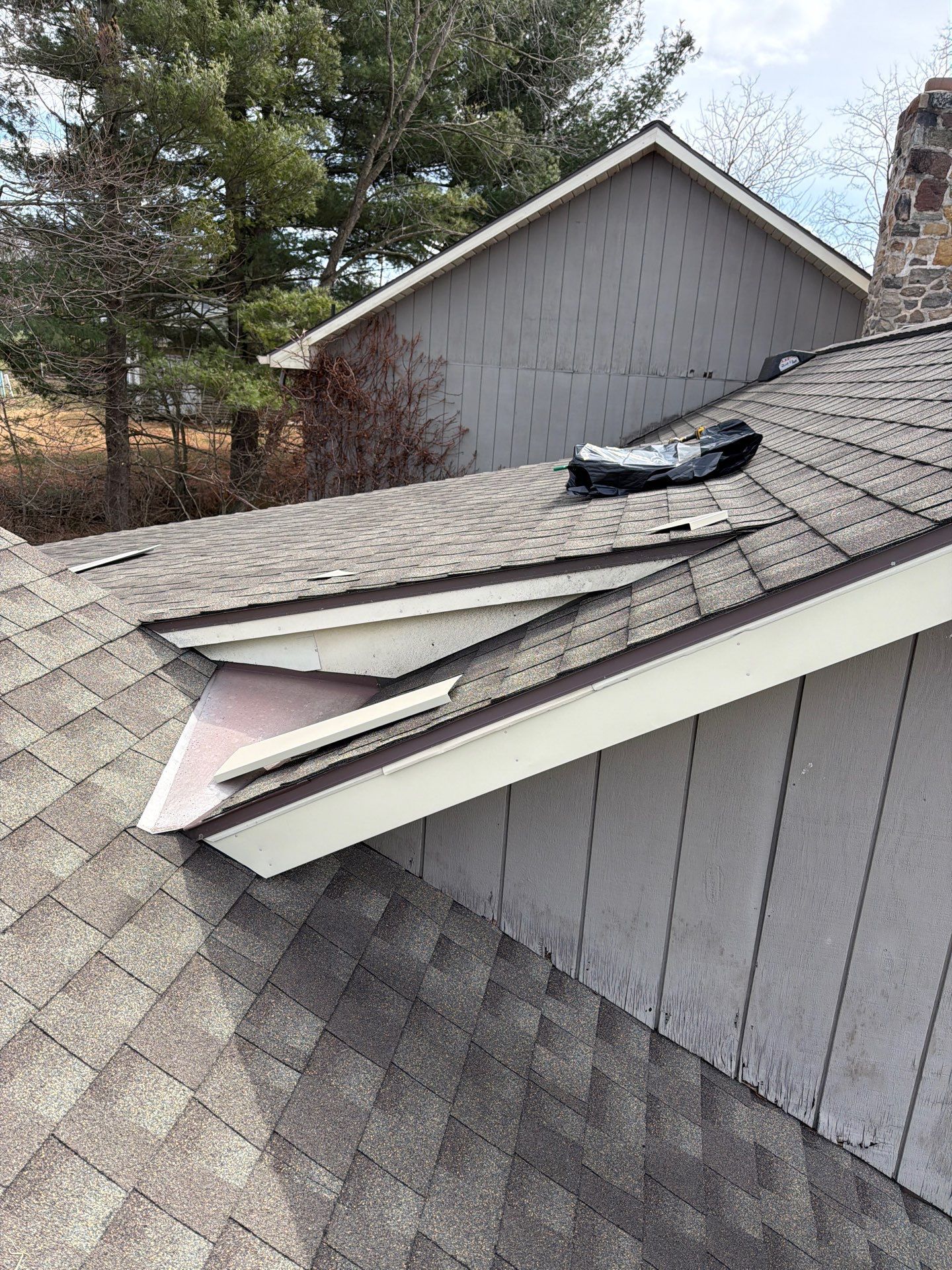 Roof repair in progress on Lewis Road by Joyland Roofing, replacing damaged flashing and repairing asphalt shingles.