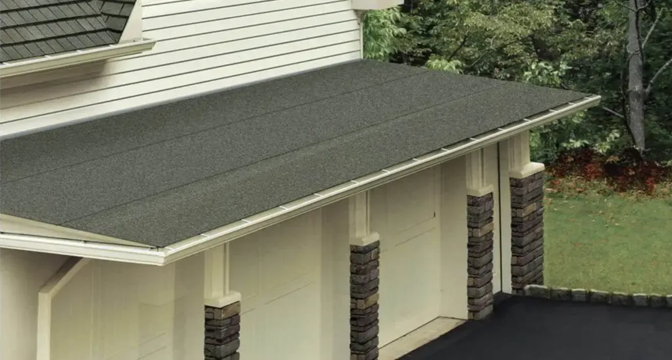 Gray shingled roof over beige house exterior with stone columns and trees nearby