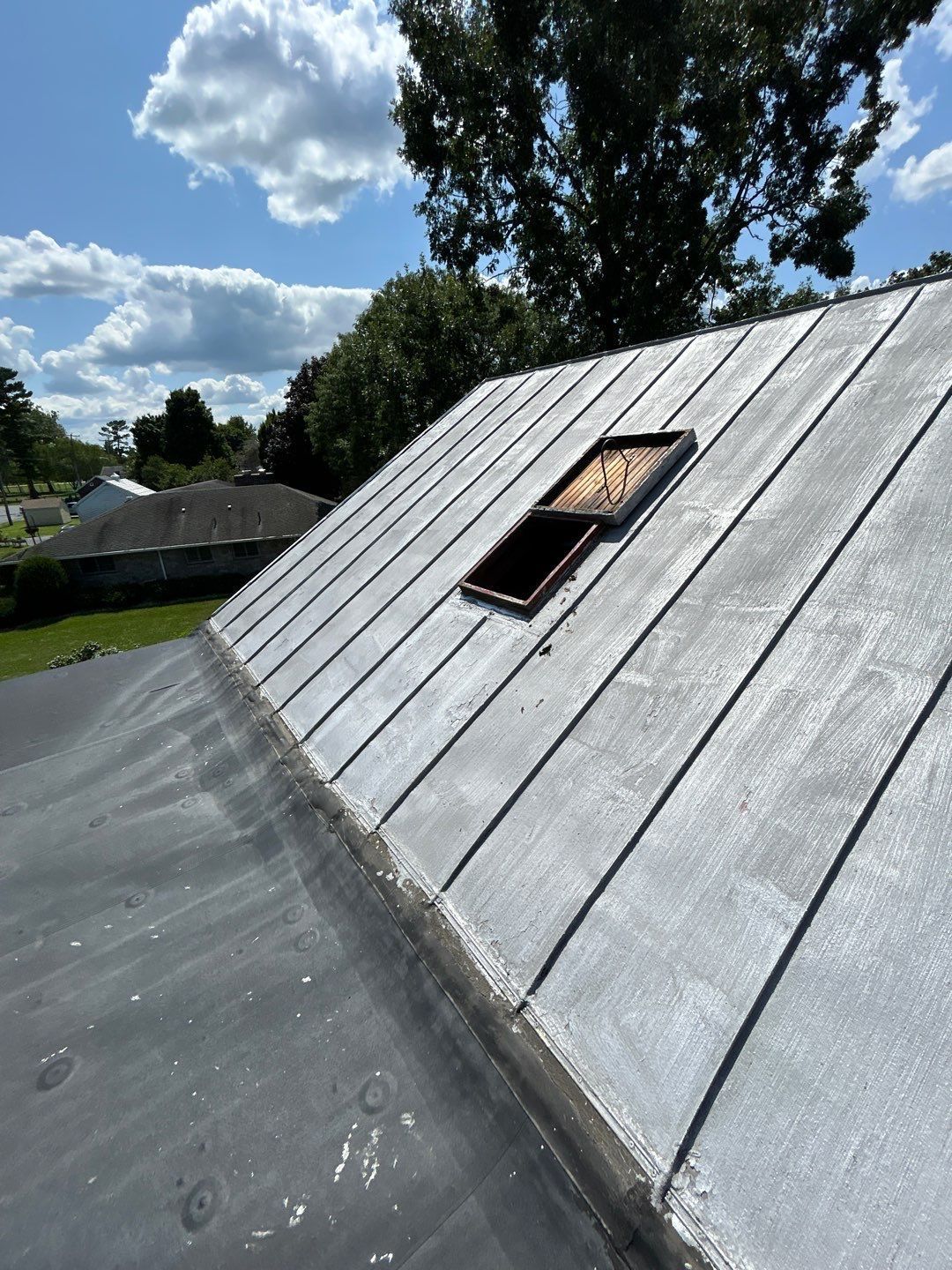 Metal roof with an open roof hatch and adjoining flat roofing system on Main Street in Shoemakersville, PA during inspection.