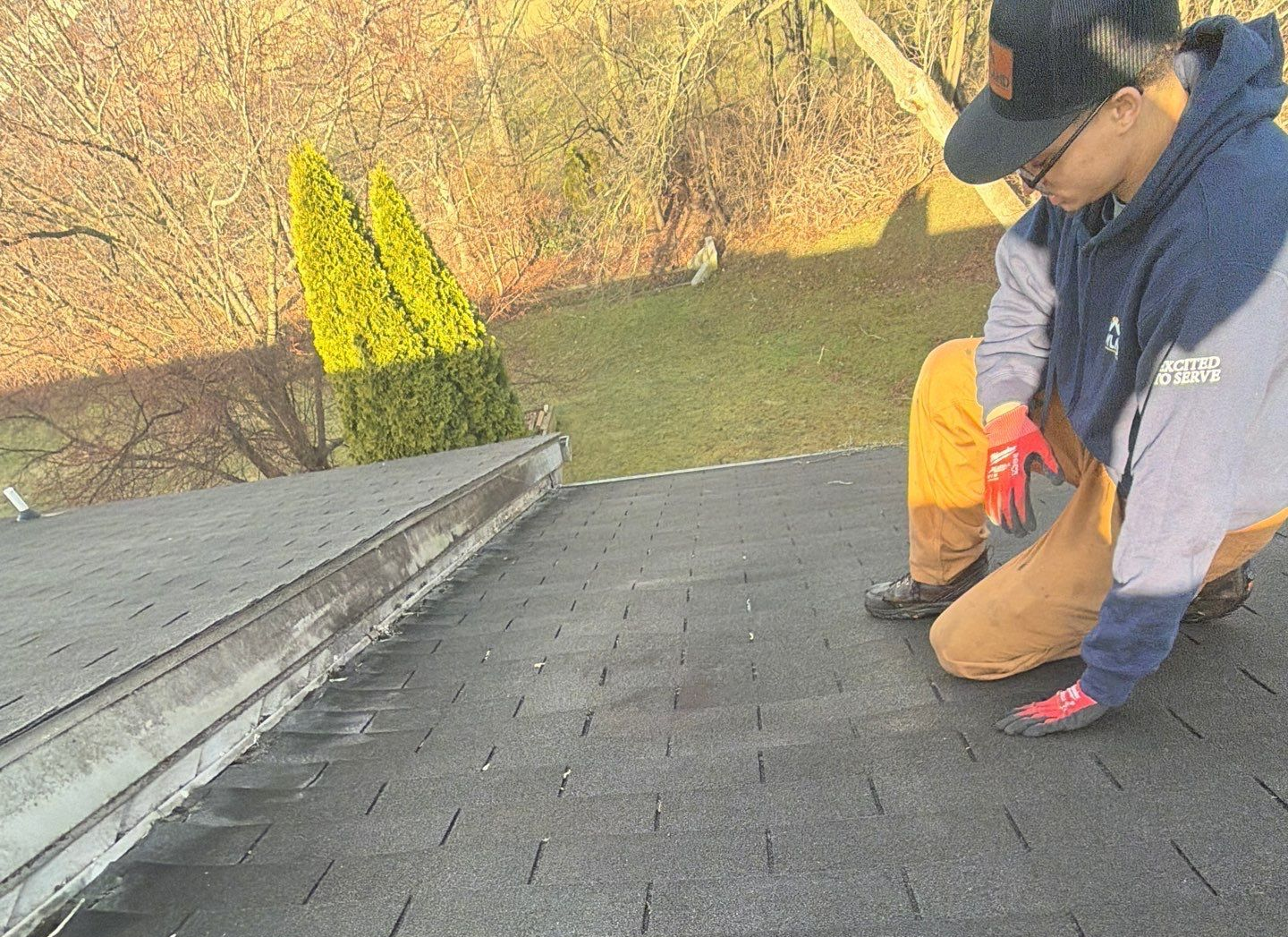 Roofing technician inspecting worn asphalt shingles and flashing along a roof transition during a residential roof repair on Meadow Lane.