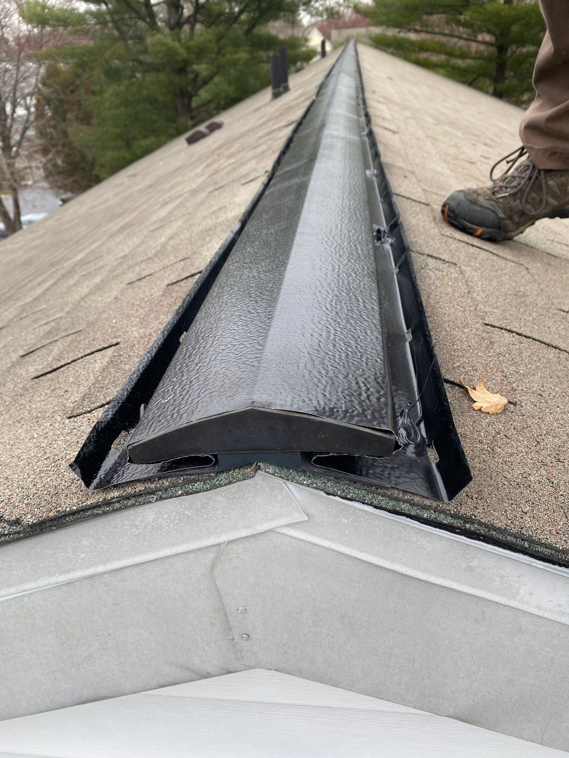New ridge vent installation on an asphalt shingle roof at Meadowood Apartments for improved attic ventilation.