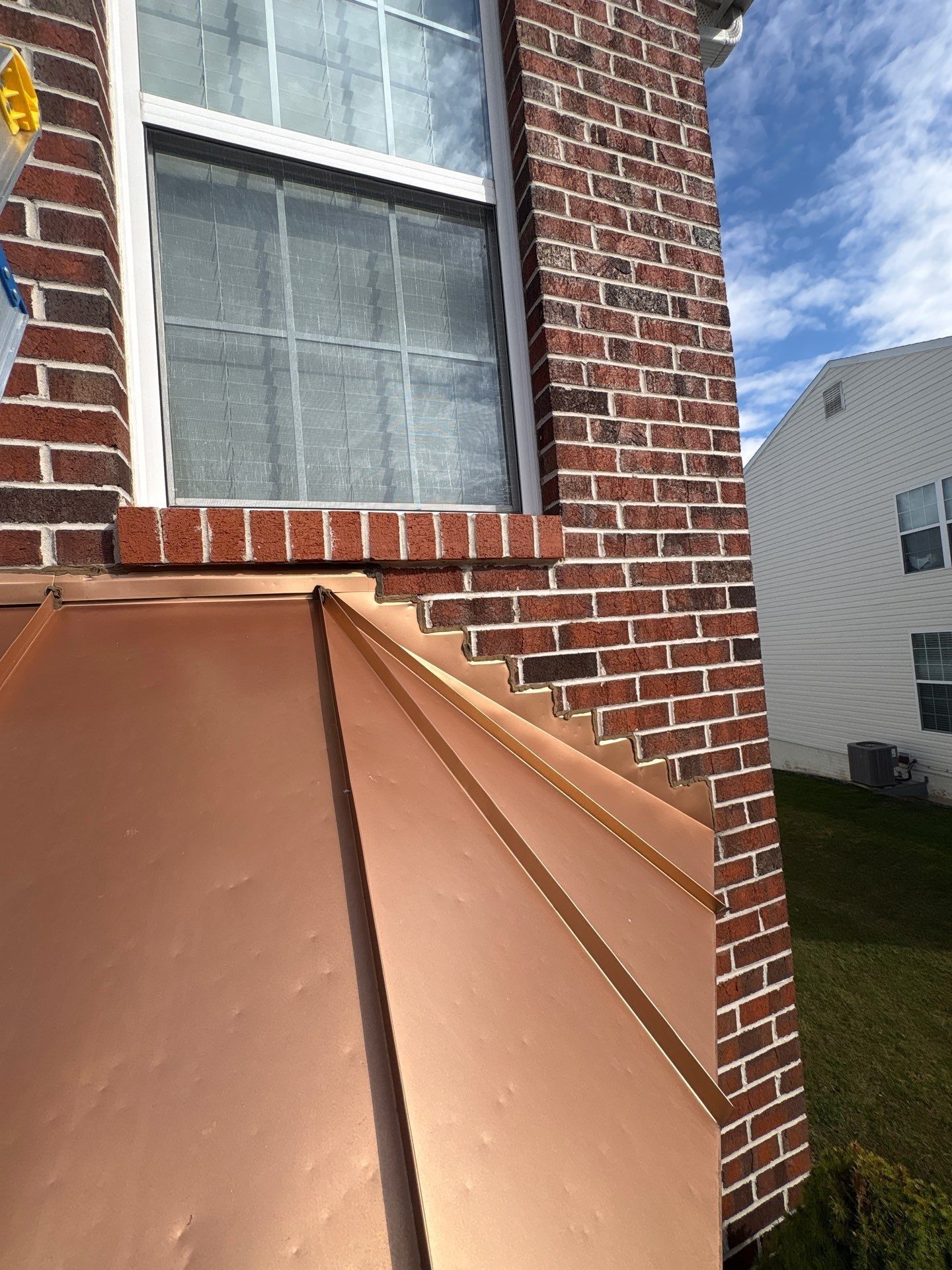 Metal roof flashing installed along a brick wall and window in Fort Washington, PA