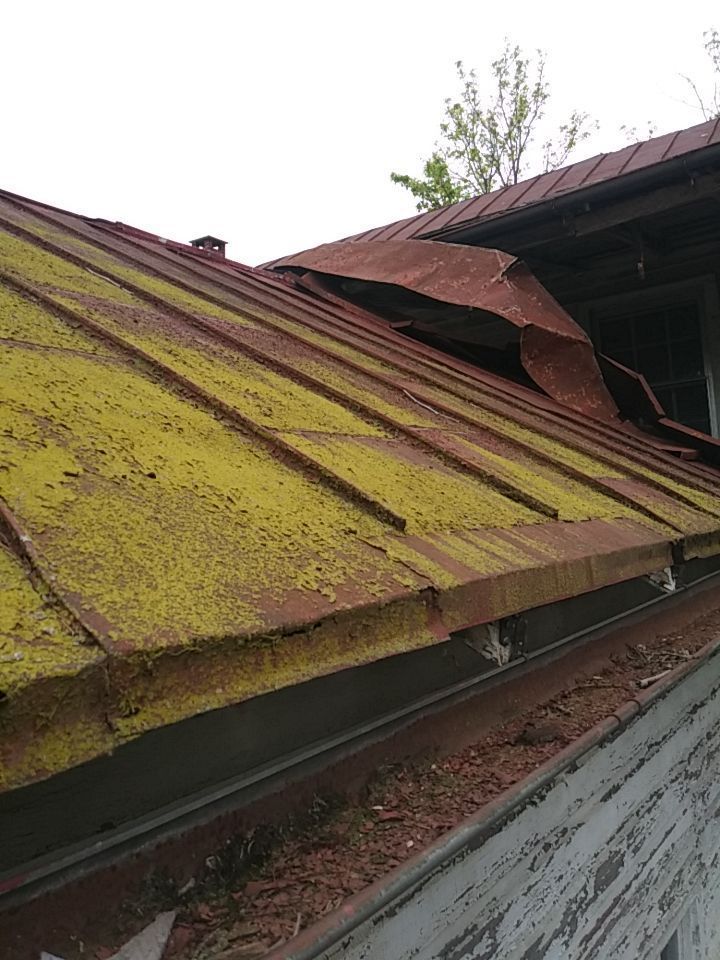Aging corrugated metal roof on Heidelberg Avenue in Schaefferstown, PA showing rust, moss growth, and severely damaged roof panels requiring replacement.