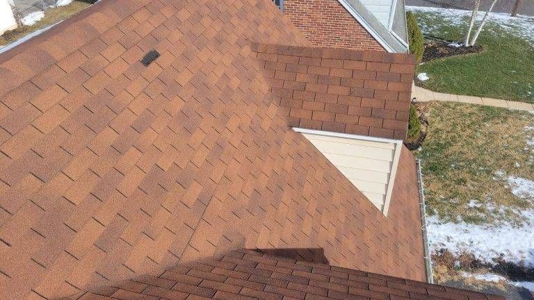 Brown asphalt shingle roof on a residential home with a triangular window.