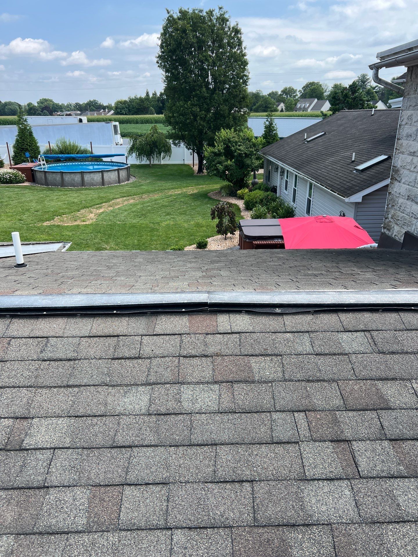 Asphalt shingle roof with a metal ridge vent installed along the roof peak during a residential roofing project.