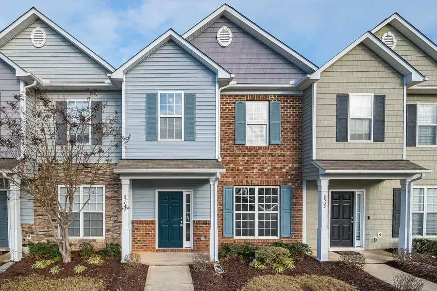 Row of townhouses with varying siding colors: blue, brick, and green.