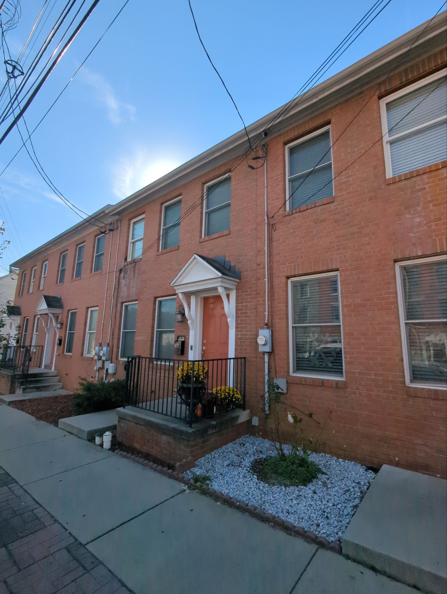 Red brick row houses with multiple windows, small entryways, and overhead power lines.