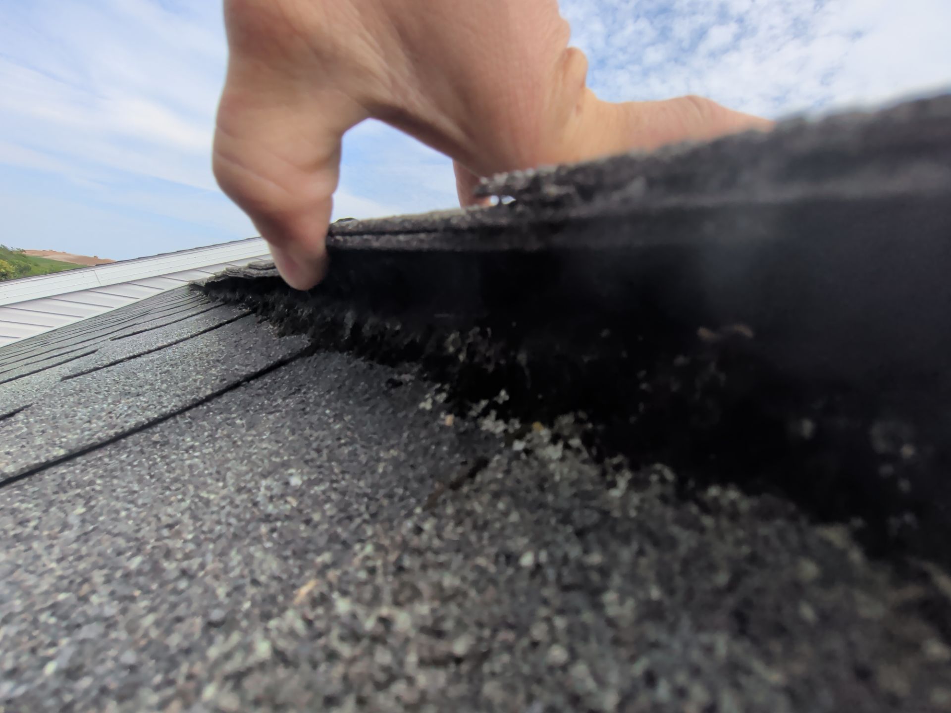 Close-up inspection of worn ridge vent materials during a roof replacement project on Ridge Road in Elizabethtown, PA showing aging ventilation components.