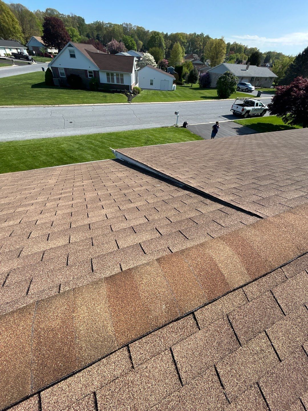 Roof shingles with a raised seam, overlooking a suburban neighborhood on a sunny day