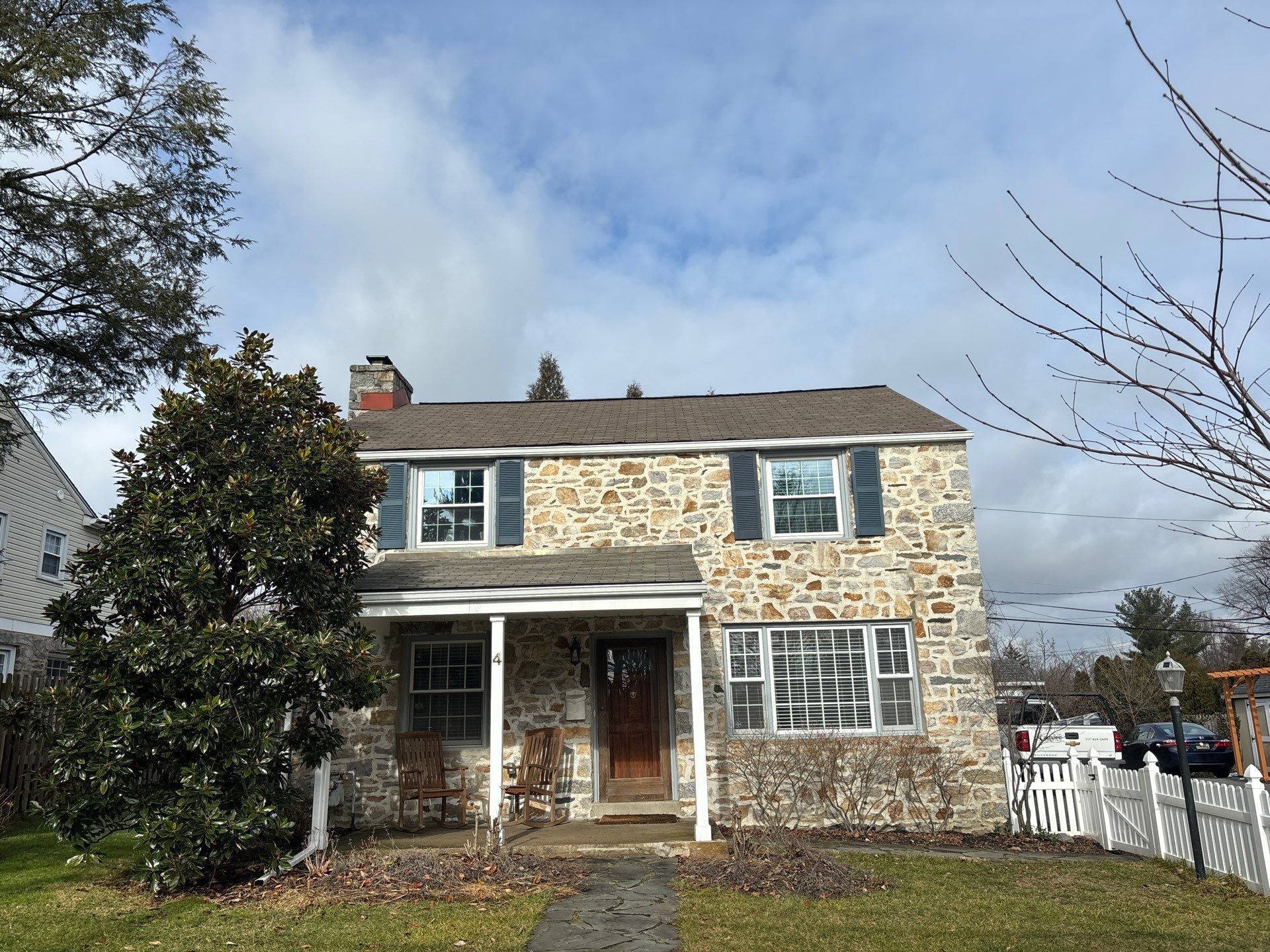 Residential asphalt shingle roof on Lowrys Lane with stone exterior and chimney