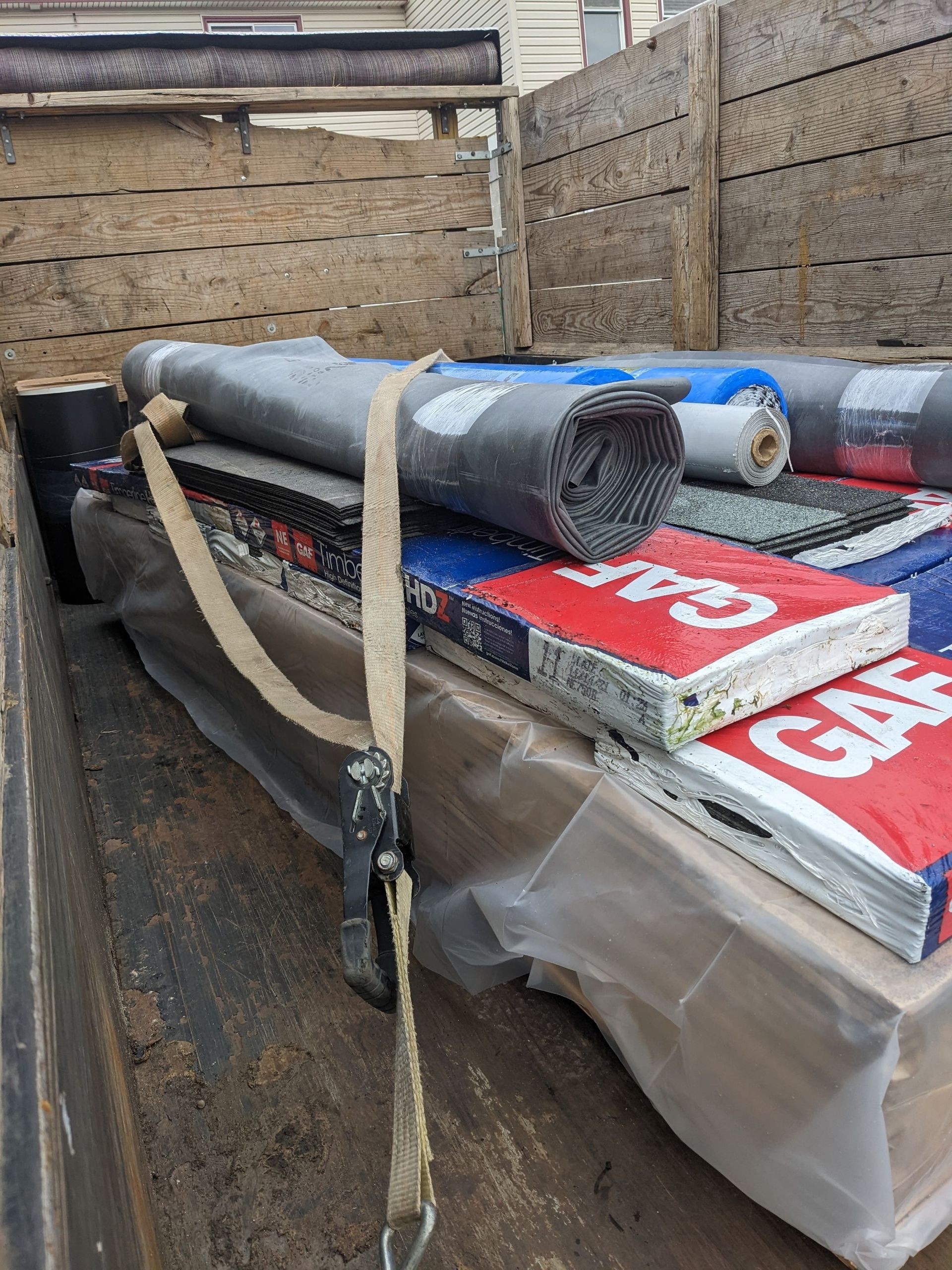 Strapped cargo load on a truck bed with rolled tarp and packages marked “CAT” and “GAP”