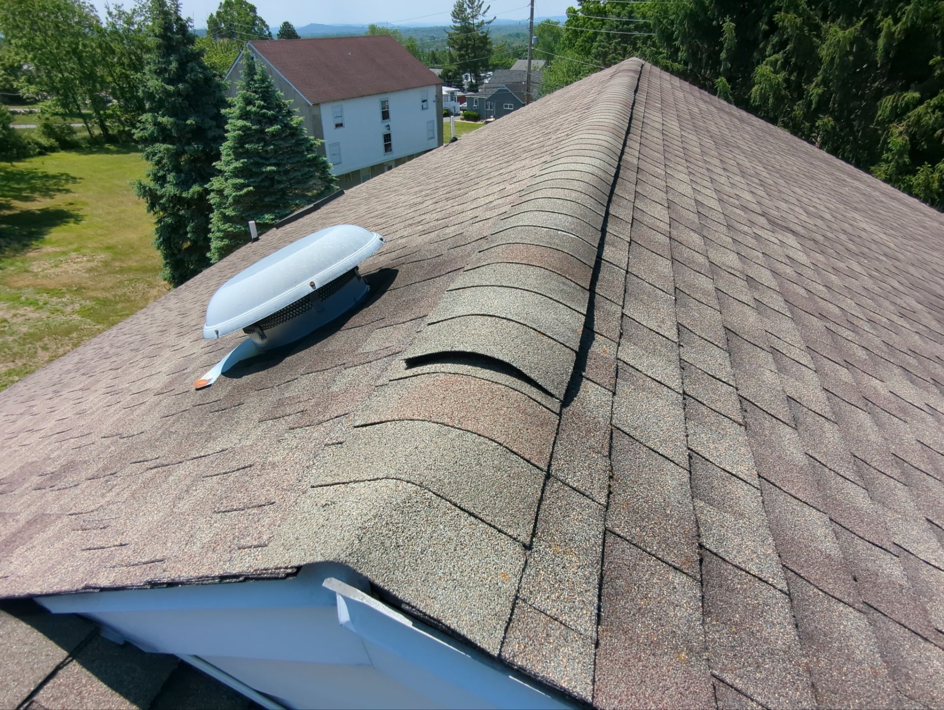 Buckled asphalt shingles and deteriorated ridge area on a residential roof in Pottstown, PA