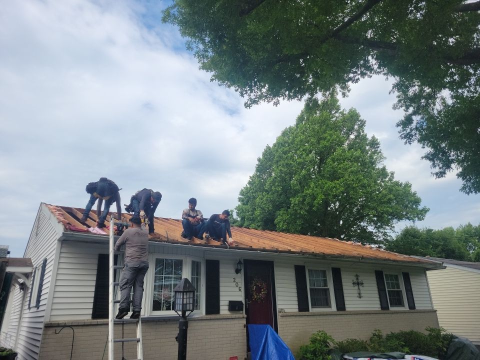 Roof replacement crew removing old roofing materials from a residential home on Forest Avenue