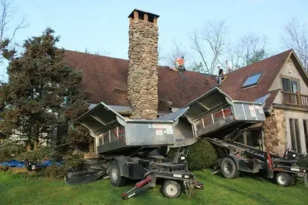 Roofing crew moving buggies loaded with materials across a job site