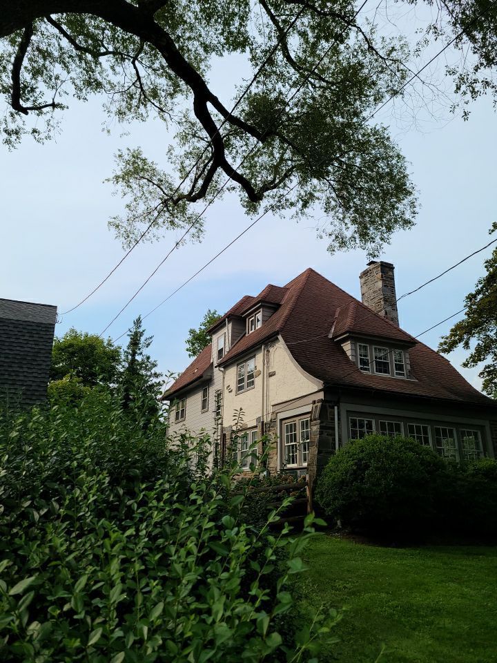 Roofing project on Glenbrook Road in Ardmore, PA showing a steeply pitched residential roof with architectural details and stone exterior