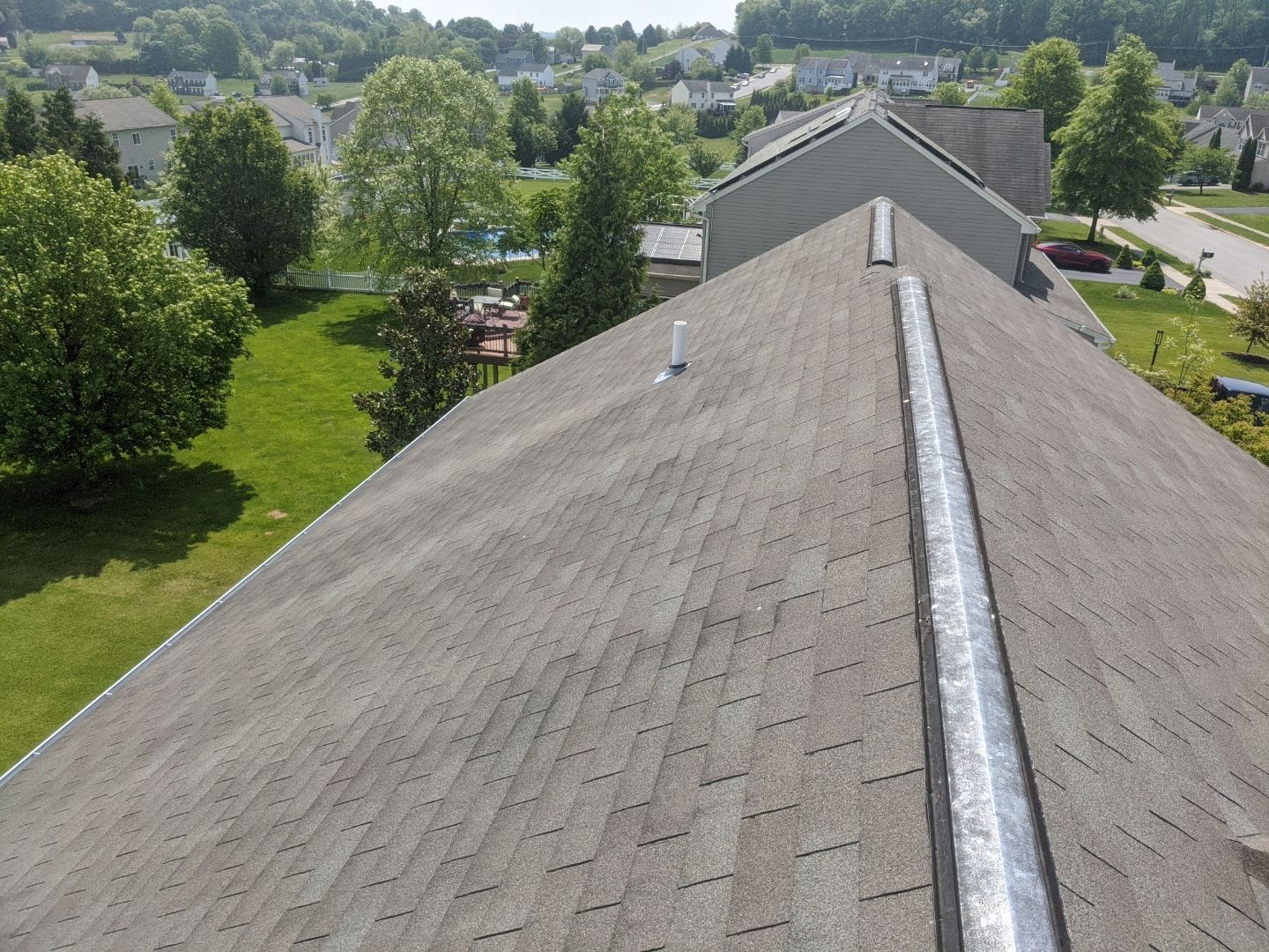 Aerial view of a residential asphalt shingle roof in York, PA showcasing a completed roofing installation by Joyland Roofing in a suburban neighborhood.