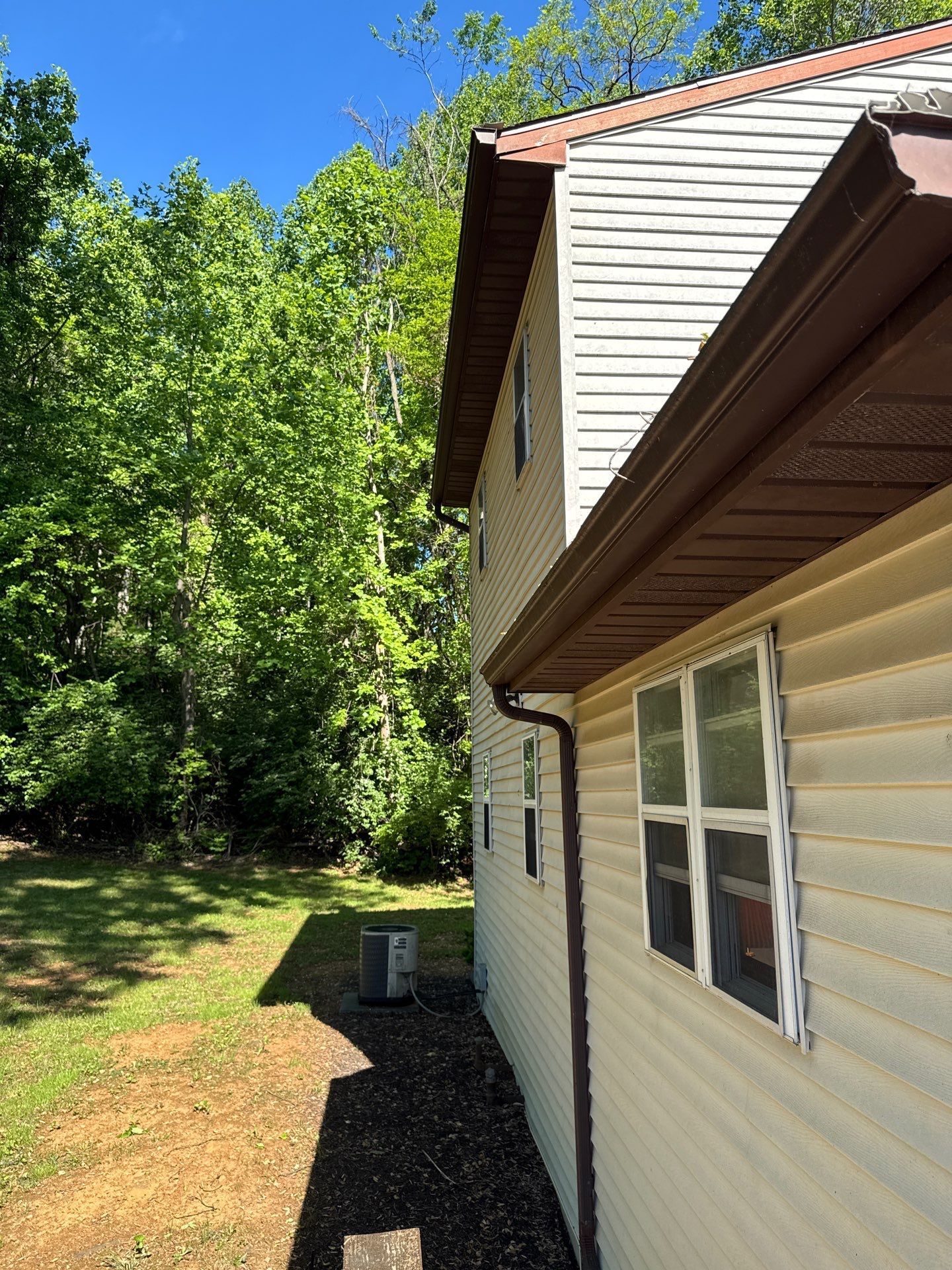 Seamless gutter installation with brown gutters and downspouts on Poplar Road in Dillsburg, PA by Joyland Roofing.