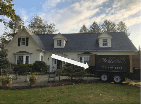 A house with a new roof, a roofing company trailer in the yard, and an arrow pointing to the house.