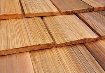 Close-up of overlapping, textured wooden shingles in various shades of brown.