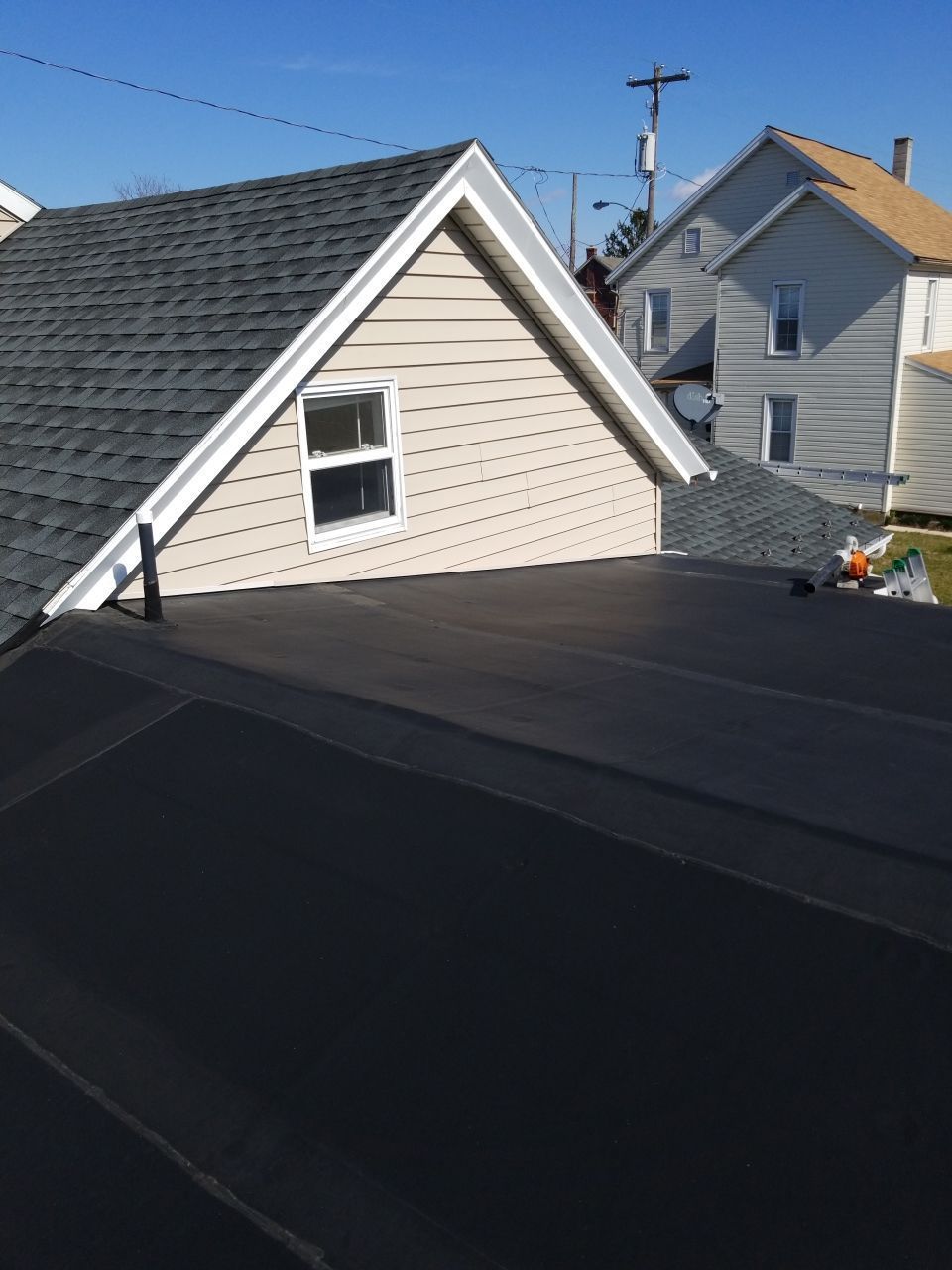 Flat EPDM rubber roofing system installed alongside an asphalt shingle roof on a residential home during a roof replacement project.