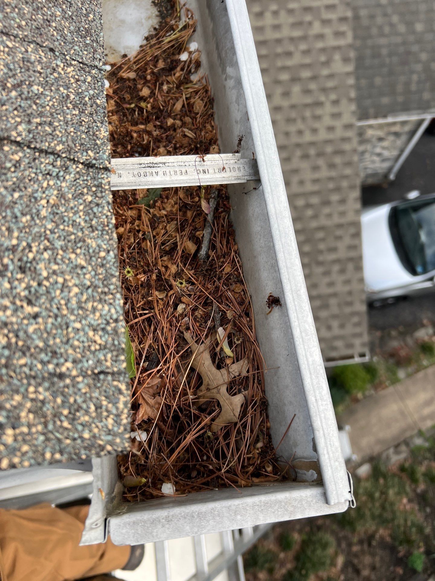 Clogged gutter filled with pine needles and leaves during a gutter repair inspection on Wingate Court in Millersville, PA.