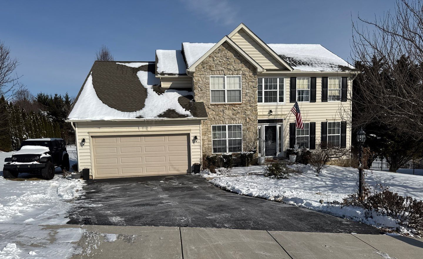 Two-story home on Red Spire Lane in Stewartstown, PA, during a winter roof inspection with snow covering portions of the asphalt shingle roof.