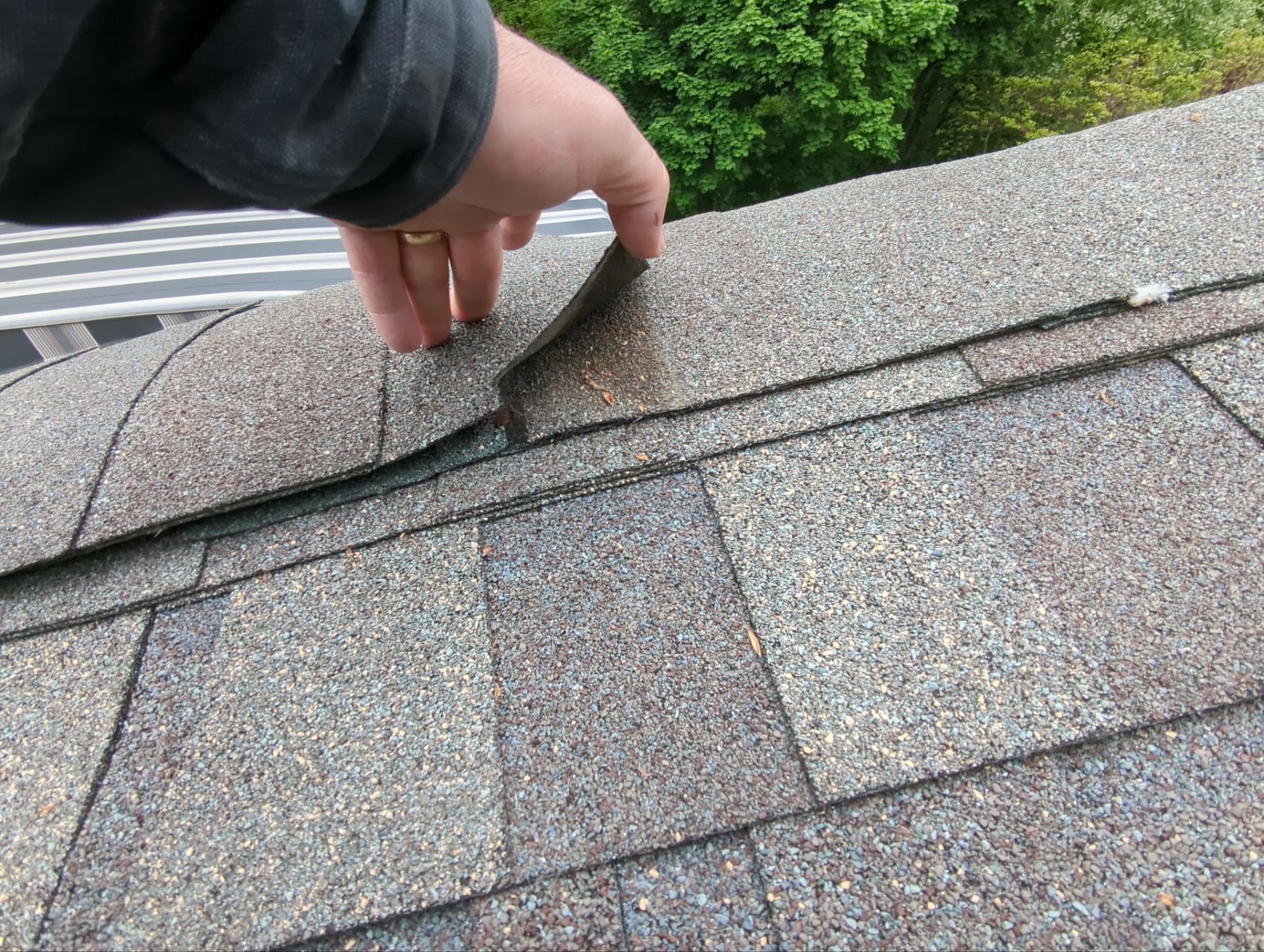 Roof replacement process showing ridge cap shingle removal and inspection on a home in Wynwood Drive, Mountville, PA.