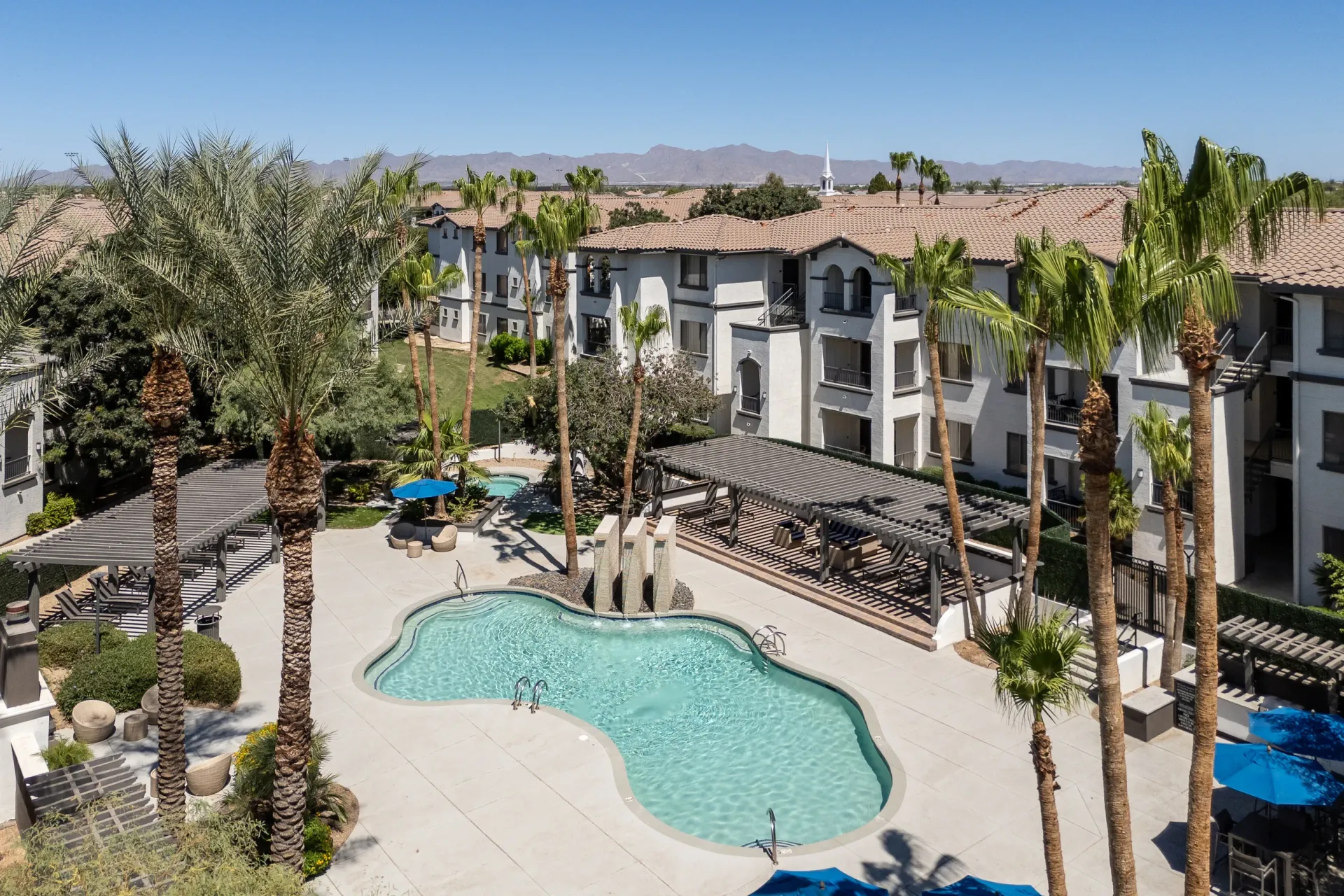 Resort-style pool and spa area with palm trees and lounge seating.