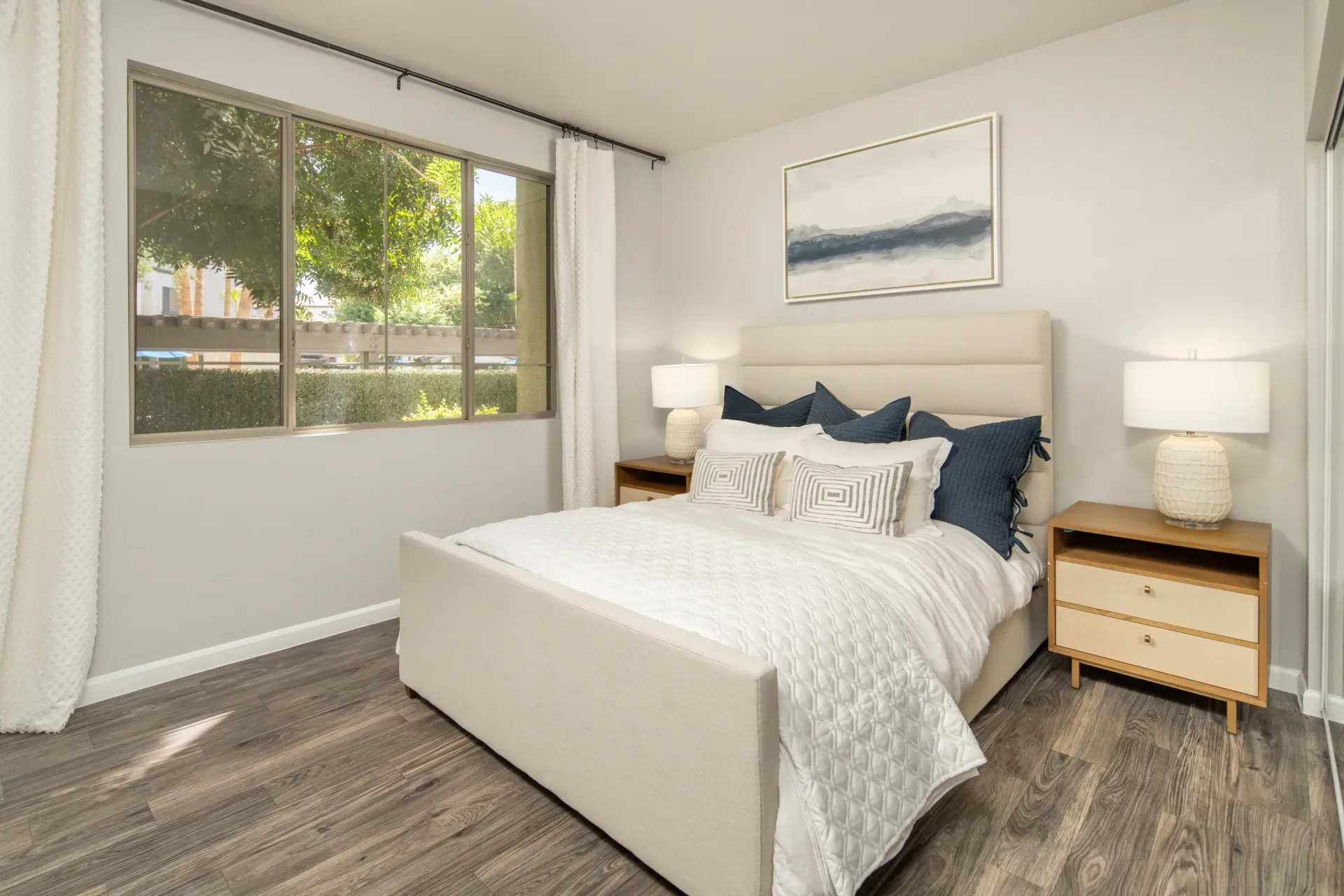 Bedroom with a queen-sized bed, nightstands, and a large window.