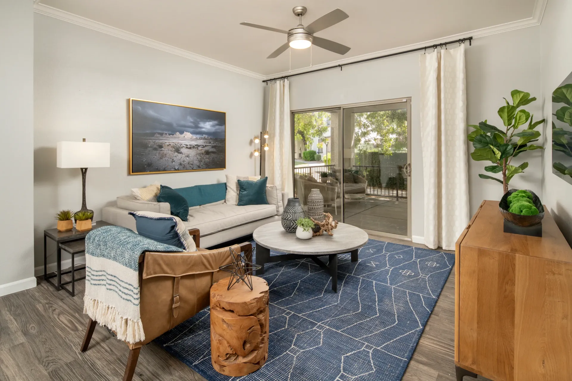 Living room with a gray couch, leather armchair, blue rug, and sliding glass door leading to a patio.