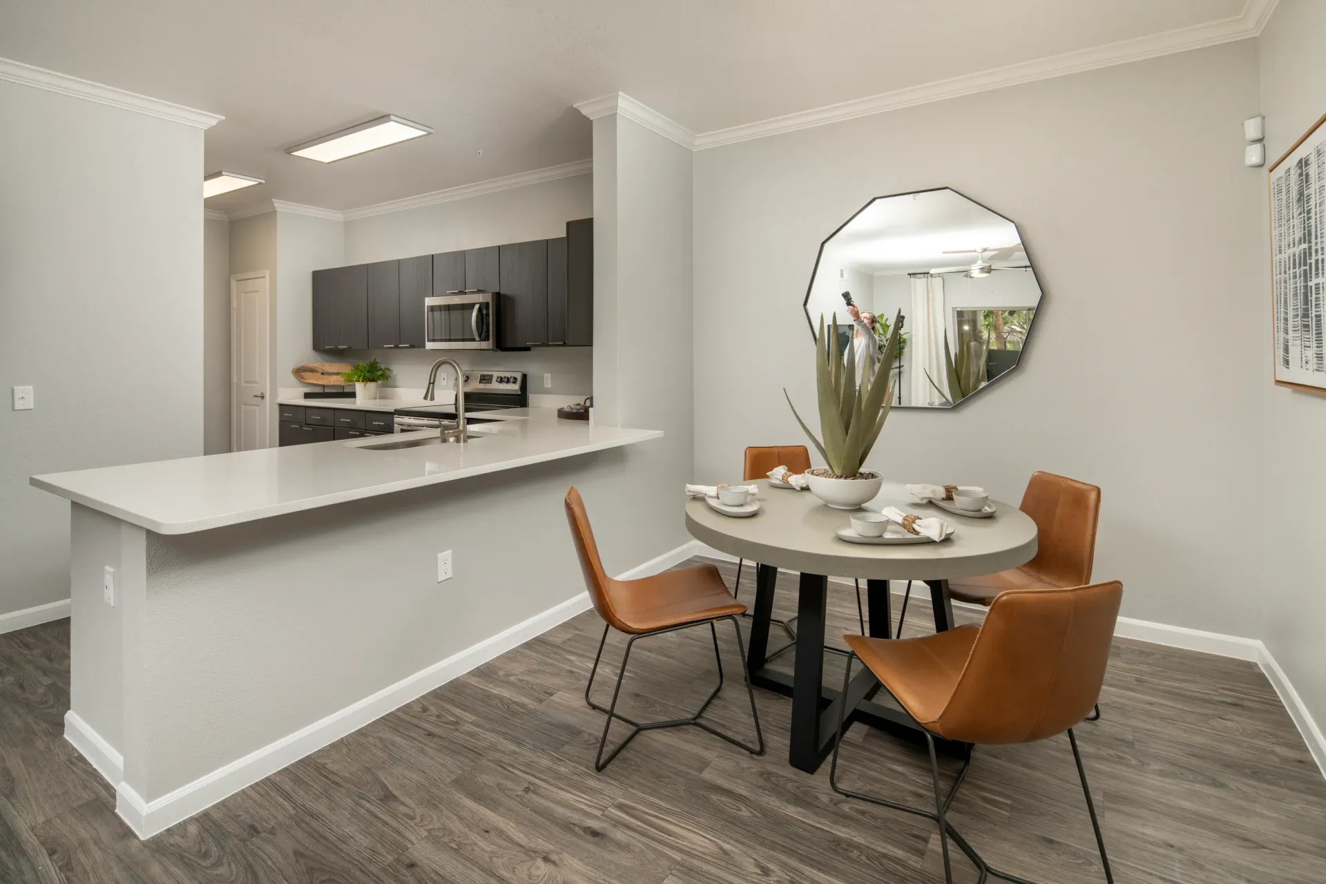 Modern kitchen and dining area with granite countertops, dark cabinets, and leather chairs.